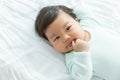 Adorable baby girl sucking thumb on the bed. Royalty Free Stock Photo