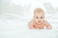 Adorable baby girl in white sunny bedroom. Newborn child relaxing and laying on belly on bed. Nursery for young children. Textile Royalty Free Stock Photo