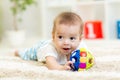 Adorable baby having fun with toy on cozy rug. Happy cheerful kid playing on the floor