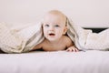 Adorable baby learning to crawl in white  bedroom. Cute funny baby lying under the blanket on bed. Little child doing tummy time Royalty Free Stock Photo