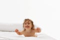 Adorable baby, little girl with wet hair lying in diaper on bed, embodying innocence and joy against white background. Royalty Free Stock Photo