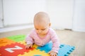 Adorable baby lying on a colorful mat with letters