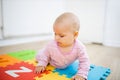 Adorable baby lying on a colorful mat with letters