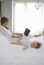 Adorable Baby Lying Beside Mother Using Laptop