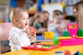 Adorable baby playing with educational toys with group of nursery kids under teacher supervision Royalty Free Stock Photo