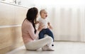 Adorable baby playing with mom, sitting on floor in kitchen Royalty Free Stock Photo