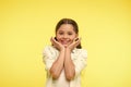 Adorable baby smiling. Full of excitement. Girl happy smiling face touches her cheeks yellow background. Pupil excited