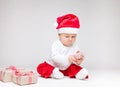 Adorable baby wearing a Santa hat opening Christmas presents Royalty Free Stock Photo