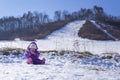 Adorable baby in a white snow in the warm suit siting in the snow