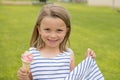 Adorable and beautiful blond young girl 6 or 7 years old eating delicious ice cream smiling happy on green grass field ba Royalty Free Stock Photo