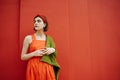 Adorable beautiful teenager girl in red dress and green jacket waiting hoping and looking side.