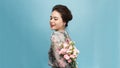 Adorable, beautiful woman holding bouquet of flowers isolated on blue background Royalty Free Stock Photo