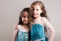 Adorable big and little sister wearing matcing blue dresses posing together happily, studio background Royalty Free Stock Photo