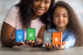 Adorable black girl and her happy mom holding toy wooden trash bins for sorting garbage, selective focus Royalty Free Stock Photo