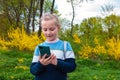 Adorable blogger child girl chatting in social media smartphone learning language listening audio books podcast outdoor Royalty Free Stock Photo