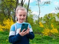 Adorable blogger child girl chatting in social media smartphone learning language listening audio books podcast outdoor Royalty Free Stock Photo