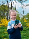 Adorable blogger child girl chatting in social media smartphone learning language listening audio books podcast outdoor Royalty Free Stock Photo