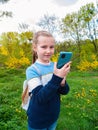 Adorable blogger child girl chatting in social media smartphone learning language listening audio books podcast outdoor Royalty Free Stock Photo