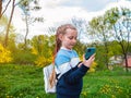 Adorable blogger child girl chatting in social media smartphone learning language listening audio books podcast outdoor. Royalty Free Stock Photo