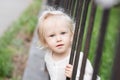 Adorable blomde baby girl is walking outdoors near the fence