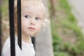 Adorable blomde baby girl is walking outdoors near the fence