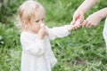 Adorable blomde baby girl is walking outdoors near the fence