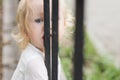 Adorable blomde baby girl is walking outdoors near the fence