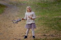 Adorable blond girl playing and jumping with her favorite toy grey cat on a beautiful autumn day. Royalty Free Stock Photo