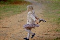 Adorable blond girl playing and jumping with her favorite toy grey cat on a beautiful autumn day. Royalty Free Stock Photo