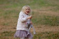 Adorable blond girl playing and jumping with her favorite toy grey cat on a beautiful autumn day. Royalty Free Stock Photo