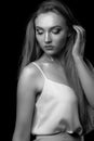 Adorable blond lady wears white silk dress posing in the shadow at studio