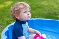 Adorable blond toddler boy playing with water, outdoors. Royalty Free Stock Photo