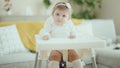 Adorable blonde baby smiling confident sitting on highchair at home Royalty Free Stock Photo