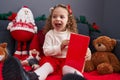 Adorable blonde girl reading book sitting on sofa by christmas decor at home Royalty Free Stock Photo