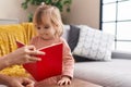 Adorable blonde girl smiling confident reading book at home Royalty Free Stock Photo