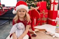 Adorable blonde girl smiling confident sitting on floor by christmas tree at home Royalty Free Stock Photo