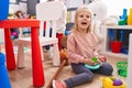 Adorable blonde girl smiling confident sitting on floor playing at kindergarten Royalty Free Stock Photo