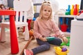 Adorable blonde girl smiling confident sitting on floor playing at kindergarten Royalty Free Stock Photo