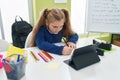 Adorable blonde girl student using touchpad writing notes at classroom Royalty Free Stock Photo