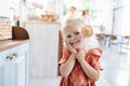 Adorable blonde little girl holding cookie on a stick, smiling at the camera.