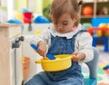 Adorable blonde toddler playing with play kitchen sitting on chair at kindergarten Royalty Free Stock Photo