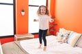Adorable blonde toddler smiling confident jumping on bed at bedroom Royalty Free Stock Photo