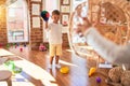 Adorable blonde twins playing basketball using wicker basket and ball around lots of toys at kindergarten Royalty Free Stock Photo