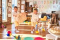 Adorable blonde twins playing basketball using wicker basket and ball around lots of toys at kindergarten Royalty Free Stock Photo