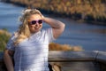 Adorable blonde woman poses at Lake of the Clouds in Porcupine Mountains wilderness state park in Michigan, looking away from