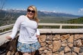 Adorable blonde woman smiles and poses for a tourist photo at the Galena Summit Overlook in the Sawtooth Mountains of Idaho