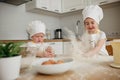 Adorable boy ad girl in chefs hats and aprons playing with the flour in the kitchen Royalty Free Stock Photo