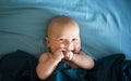 Adorable boy in the bedroom. A newborn baby is resting in a blue-colored bed.