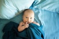 Adorable boy in the bedroom. A newborn baby is resting in a blue-colored bed.