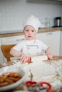 Adorable boy in chef hat and apron rolling out pastry dough Royalty Free Stock Photo